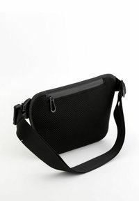Bolso negro de hombro con un exterior de malla texturizada, cierre con cremallera y correa ajustable. Presenta una forma rectangular y elegante.