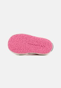 Růžová gumová podešev s texturovaným povrchem a bílým okrajem. Tištěné logo ve středu, zpevněné kontrastním černým lemem.