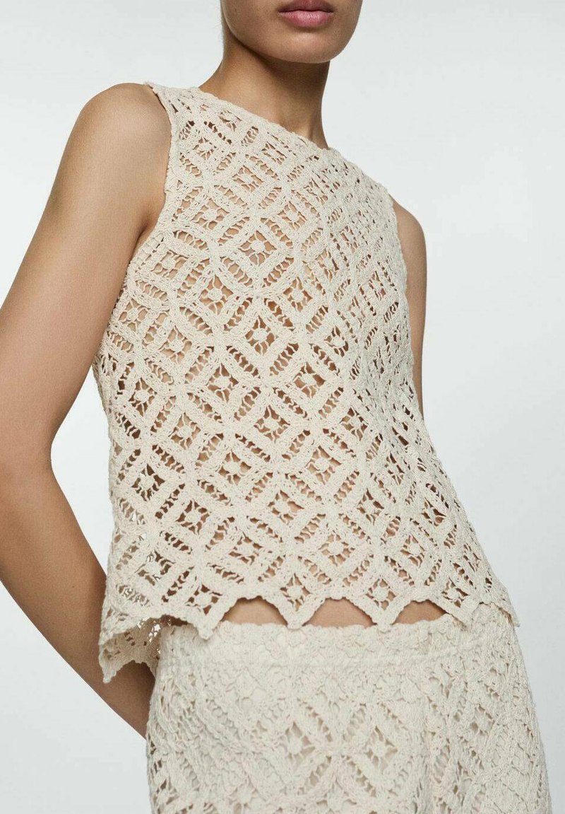 Crocheted sleeveless top in beige with a diamond pattern, featuring a scalloped hem and open weave texture for breathability and style.