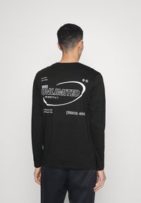 Schwarzes Langarm-T-Shirt mit weißen Grafiken auf der Rückseite, einschließlich "UNLIMITED", "2022" und "ERROR 404". Weicher Stoff mit lässiger Passform.