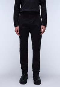 Czarne spodnie cargo z bocznymi kieszeniami, wykonane z gładkiego materiału. Model z dopasowanym stanem i zwężanymi nogawkami, zestawione z czarnym obuwiem.