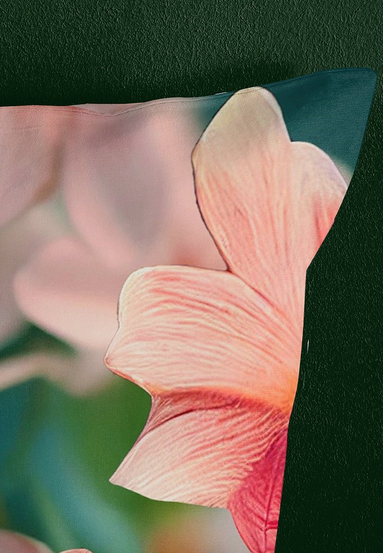 Eckkissen aus blumenmusterndem Stoff mit einem sanften rosa Blütenblatt, glatter Textur und subtilen Farbverlauf vor einem dunklen Hintergrund.