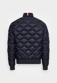Marineblå quilted puffer jakke med diamantmønster, ribbede manchetter og stribe detaljer på kraven. Fremstillet af letvægtsmateriale.