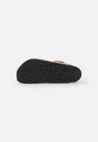 Black rubber sole with a wavy pattern, light brown and pink upper material; features gold hardware and a single adjustable strap.