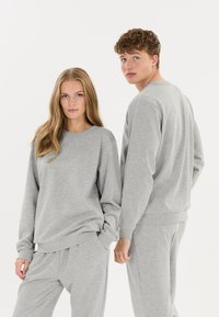 Grå bomulds sweatshirt og sweatpants sæt, med en afslappet pasform, rund halsudskæring og ribbede manchetter. Glat tekstur med minimalt mønster.