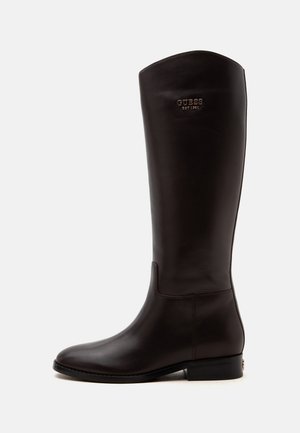 Botte noire en cuir hautes avec un petit talon et le logo Guess embossé près du haut sur le côté extérieur.