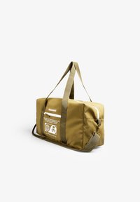 Bolsa de viaje color verde oliva con correas ajustables, cierre de cremallera y un gran parche gráfico que muestra íconos y texto en un lado.