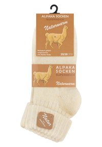 Alpakawollsocken in hellem Cremeton, mit geripptem Bündchen, die Verpackung zeigt eine Illustration eines Alpaka, Größe 35/38, beschriftet mit "Naturwarm."
