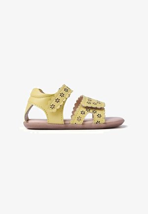 Sandalo giallo per bambino con due cinturini regolabili caratterizzati da bordi smerlati e ritagli a forma di fiore su una morbida suola marrone.
