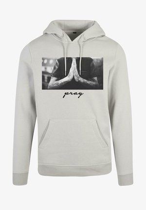 Gaiši pelēks kapučjaks ar priekšējo kabatu. Izceļas ar melnbaltu grafiku, kurā redzamas rokas lūgšanās pozīcijā un vārds "lūdz" kursīvos.