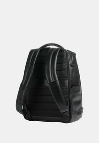 Zaino in pelle nera con spallacci imbottiti, un pannello testurizzato e un design elegante e angolare. Dotato di manico superiore e chiusura con zip.