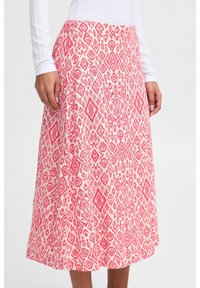 Jupe longueur genoux avec un motif géométrique rose et blanc, offrant une coupe décontractée et une texture de tissu lisse. Ceinture élastique visible.