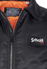 Schwarze Nylon-Bomberjacke mit orangefarbigem Innenfutter, Frontreißverschluss und Schott-Logo-Patch. Mit Kragen und geripptem Saum.