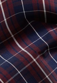 Bomullstyg med mörkblå bakgrund, med ett röd- och vitrutigt plädmönster med ränder i olika storlekar. Mjuk textur.