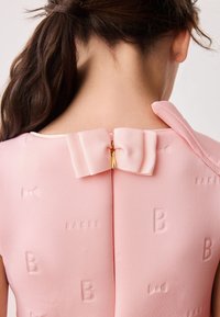 Abito rosa con texture a forma di 'B' e motivi a fiocco, caratterizzato da una chiusura posteriore con un accento a fiocco. Tessuto morbido, design aderente.