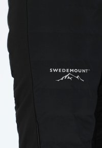 Black padded pants featuring a smooth texture. The visible logo "SWEDEMOUNT" in white is accompanied by a mountain graphic, accentuating outdoor design.