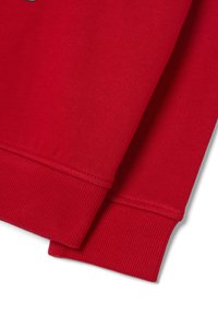 Nahaufnahme von roten Sweatshirtärmeln mit gerippten Bündchen und genähten Säumen auf einem weißen Hintergrund.