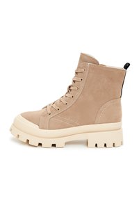 Beige suède enkellaarsjes met een gestructureerd oppervlak, ronde neus, vetersluiting aan de voorkant en stevige witte chunky zool. Zwarte trekband aan de achterkant.