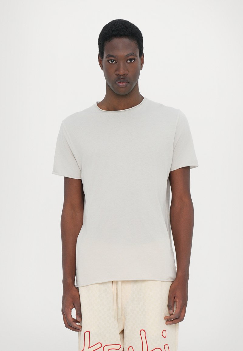 Camiseta de algodón gris claro con cuello redondo, mangas cortas y un corte relajado. Textura suave, diseño minimalista, sin patrones notables.