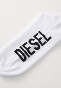 Calzini alla caviglia in cotone bianco con il logo nero "DIESEL" in bold, dal texture liscia e design semplice, adatti per un abbigliamento casual.