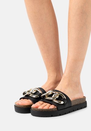 Sandales noires à glissière, dotées d'un accent de chaîne argentée épaisse sur les brides, d'une semelle intérieure en liège texturée et d'une semelle extérieure en caoutchouc durable.