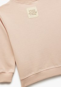 Lichtroze sweatshirt met ribbels aan de mouwen en de halslijn. Voorzien van een vierkante stoffen patch met bedrukt tekst in een contrasterende kleur. Zachte textuur.