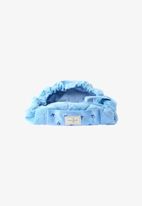 Bolsa de tela azul claro con parte superior recogida, textura acolchada y pequeño patrón de lazo azul. Presenta una etiqueta que dice "The Flat Lay Co."