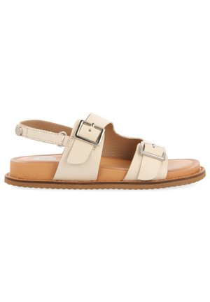 Sandalia de cuero beige con dos correas anchas, hebillas plateadas y una plantilla acolchada color bronce. Suela plana con un borde de goma texturizada.