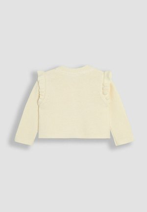 Suéter de punto color crema con mangas largas, que presenta acentos fruncidos en los hombros y un escote redondo. Superficie texturizada, diseño corto.