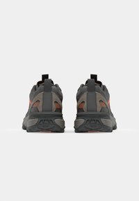 Gray athletic shoes with a textured synthetic upper, orange accents, and a thick black rubber sole. Features a pull tab at the heel.