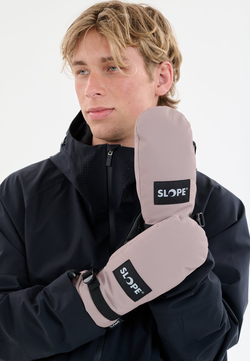 Des moufles roses avec une texture lisse, ornées d'un logo SLOPE noir et de sangles réglables au niveau des poignets, portées sur une veste sombre.
