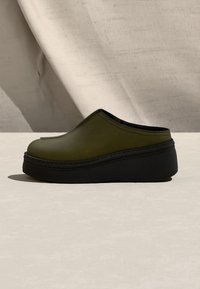 Olívazöld bebújós klumpák lekerekített orral, testhez simuló kialakítással és fekete talppal. Simább textúra, látható varráselemekkel.