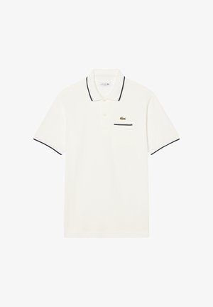 Polo blanca de manga corta con ribete negro en el cuello y las mangas, tapeta con botones y un pequeño logo de cocodrilo verde en el pecho.
