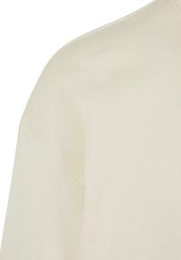 Helle cremefarbene Baumwoll-T-Shirt mit entspannter Passform, das eine glatte Textur und einen rundlichen Halsausschnitt aufweist. Die Nahtdetails sind auf der Schulter sichtbar.