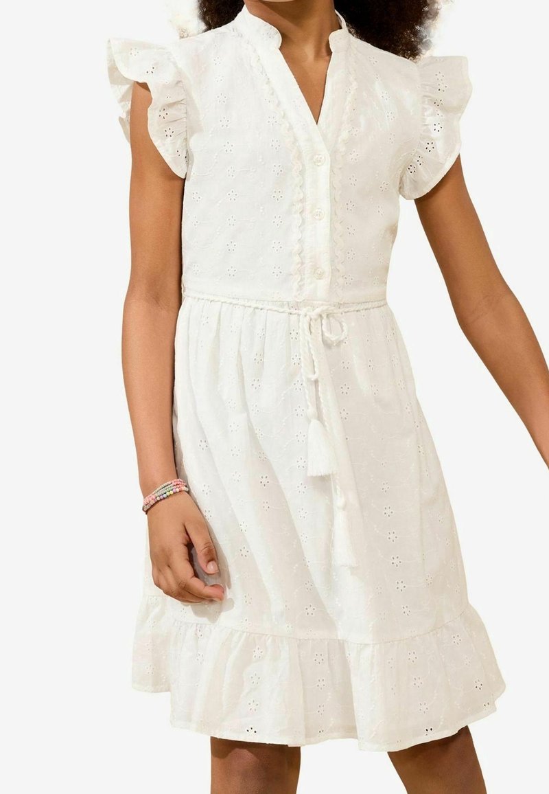 Robe en coton blanc avec des manches courtes à volants, devant à boutons et taille à nouer. Présente des motifs à œillets et un ourlet évasé.