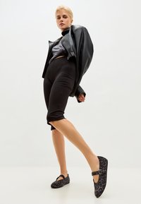 Black leather bomber jacket, grey crop top, black capri leggings, and black leopard print flats with a strap and buckle detail.