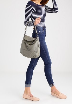 Borsa a spalla in pelle grigia con patta ripiegabile, finitura testurizzata e accessori in argento, abbinata a una maglietta a righe e jeans skinny blu.