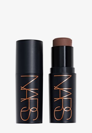 Sort cylindrisk makeup-stift og hætte med kobberfarvet NARS-logo, stiften er delvist trukket ud og viser brunt produkt indeni.
