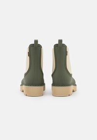 Stivali Chelsea verdi in gomma con pannelli elastici beige, suole texturizzate e linguette a ciclo sul tallone.