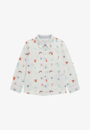 Chemise blanche à manches longues avec des boutons, ornée de petits symboles colorés comprenant des arcs-en-ciel, des signes de paix, des points d'interrogation et des logos "GUESS".