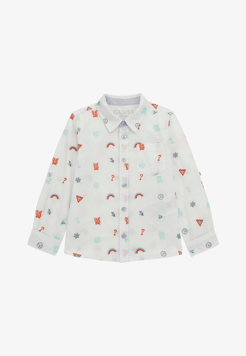 Chemise blanche à manches longues avec des boutons, ornée de petits symboles colorés comprenant des arcs-en-ciel, des signes de paix, des points d'interrogation et des logos "GUESS".
