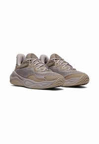 Lichtbruine sportieve schoenen gemaakt van mesh en suede, met een gestructureerde zool, gevoerd kraag en reflecterende accenten aan de zijkanten.