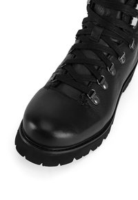 Czarny skórzany but trekkingowy z wzmocnionym noskiem, metalowymi oczkami i grubą gumową podeszwą. Charakteryzuje się teksturowaną powierzchnią i sznurowanym designem.