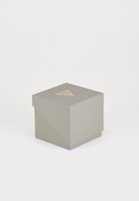 Scatola di carta grigia con una finitura testurizzata, caratterizzata da lati angolari e un logo triangolare dorato sulla superficie superiore. Misura circa 3x3x3 pollici.