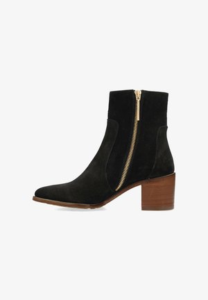 Botín negro de ante con puntera afilada, que cuenta con un cierre lateral dorado y un tacón de bloque de madera marrón. Textura suave, diseño minimalista.