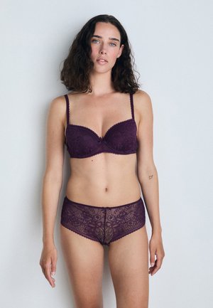 Lila spetsbh och matchande boyshorts med blommönster, vågiga kanter och mjuk textur, med justerbara band och dekorativa detaljer.