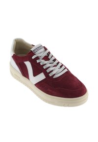 Sneaker rosso in suede con dettagli bianchi in pelle, superficie testurizzata, perforazioni sulle punte e lacci grigi. Logo del marchio sulla linguetta.
