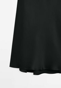 Sort satin nederdel med en glat tekstur, flydende design og en asymmetrisk kant. Enkel og elegant fremtoning.