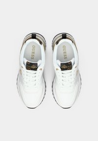 Scarpe sportive bianche con una tomaia in pelle testurizzata, dettagli dorati e un interno a motivo. Presentano una suola in gomma nera e un sistema di allacciatura.
