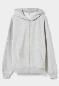 Sudadera con cremallera de color gris claro, con bolsillos frontales y capucha, exhibida en plano sobre un fondo blanco.